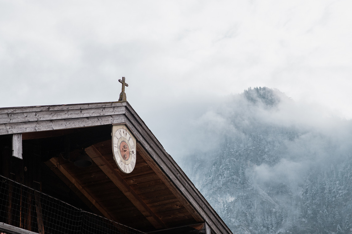 The historic clock on the gable of the Blaahaus is set against the backdrop of snow-capped Kiefersfelden mountain