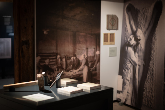 This is an excerpt from the 'Marble I' exhibition room. In this room, you can experience different chiselled stone surfaces by touching them. There are also large-scale impressions from the marble stone processing workshop in front of them.