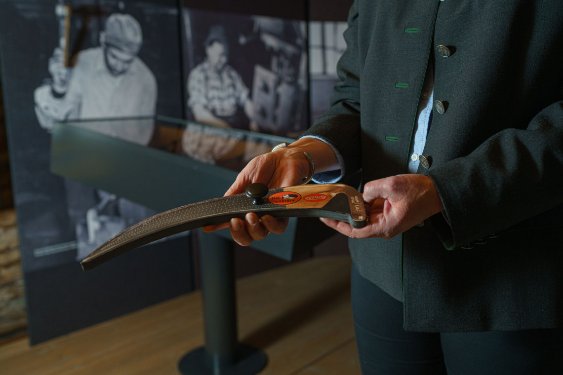 A woman holds a miniature scythe of the ‘Scythe Memory’ interactive station in the scythe room