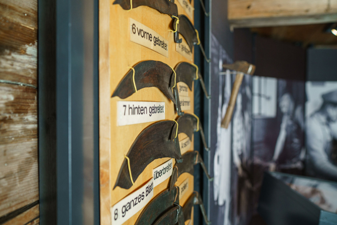 The work steps are explained. This is done using various scythe rings on a display hanging ont the wall.